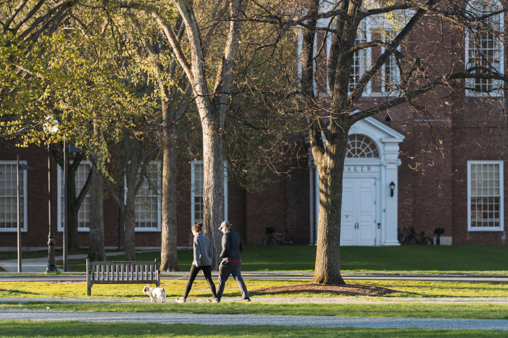 Two people walk a dog across the Dartmouth Green.