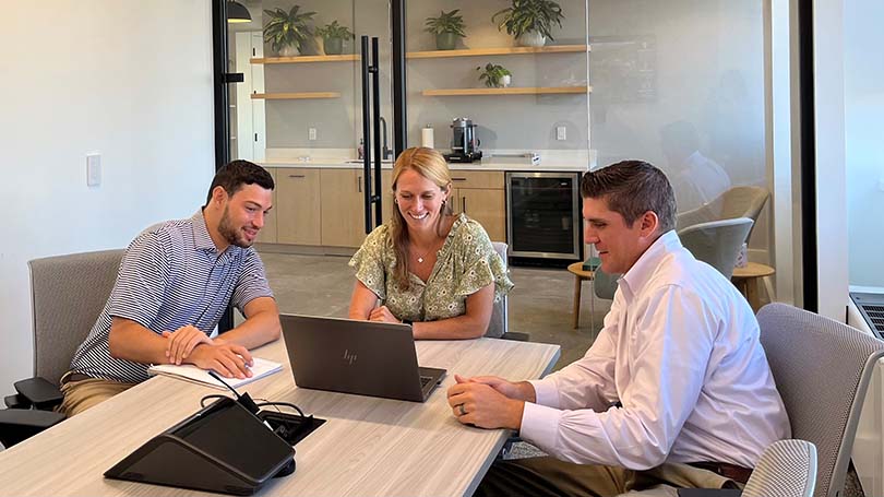 Three staff members sitting at a conference table.